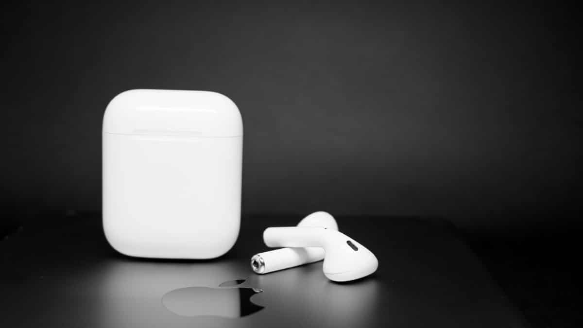 Close-up of wireless earbuds and charging case on a sleek dark background, showcasing modern design.