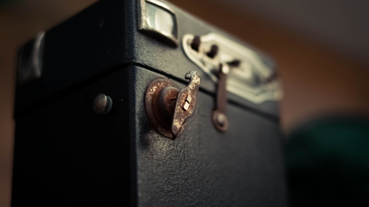 Soft focus of rusty clasp on black case of retro photo camera on black background