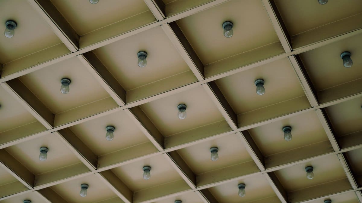 A modern geometric ceiling design featuring a grid pattern with light bulbs for architectural aesthetics.