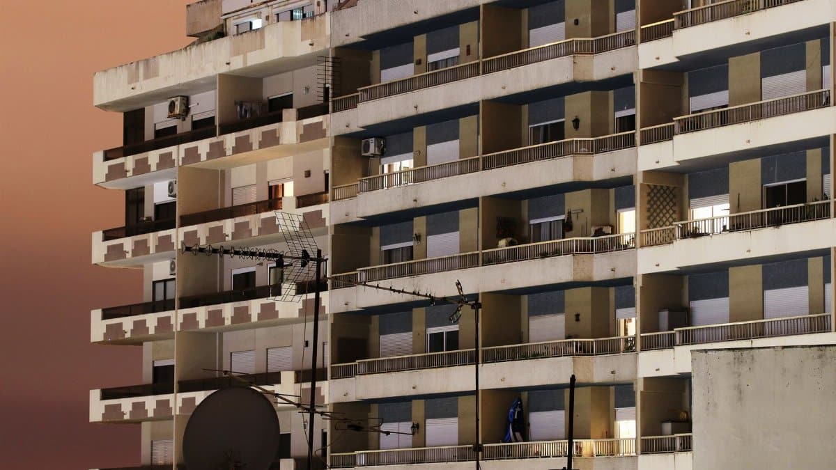 A modern residential building in Almada, Portugal, captured at dusk with a dramatic sky.
