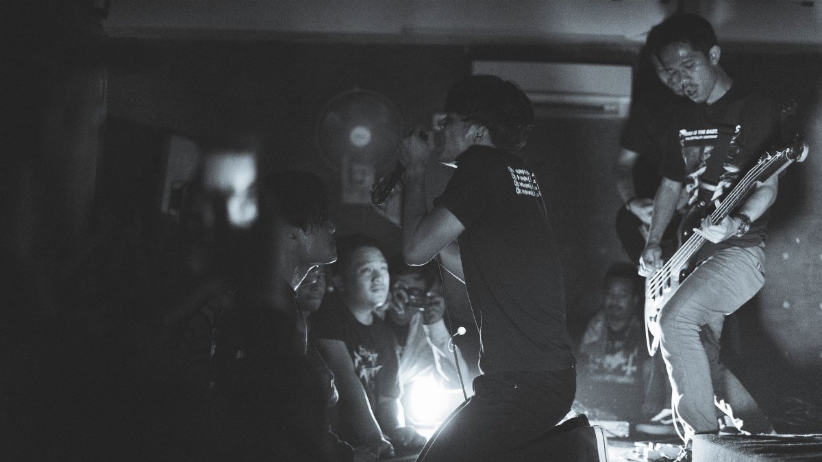 Energetic black and white photo capturing a live band performance with an enthusiastic audience.