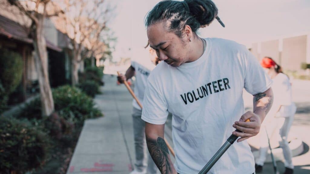 Volunteers in white shirts clean a city sidewalk, promoting community spirit and teamwork.