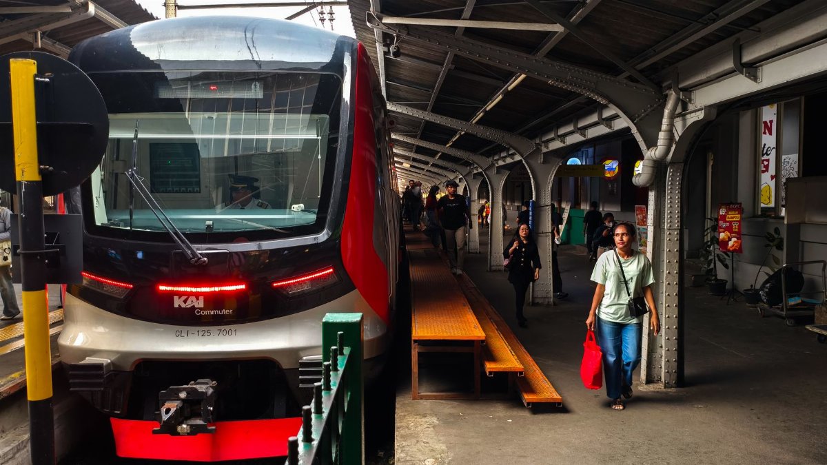 KAI Commuter train at a bustling Jakarta station, showcasing urban transit.