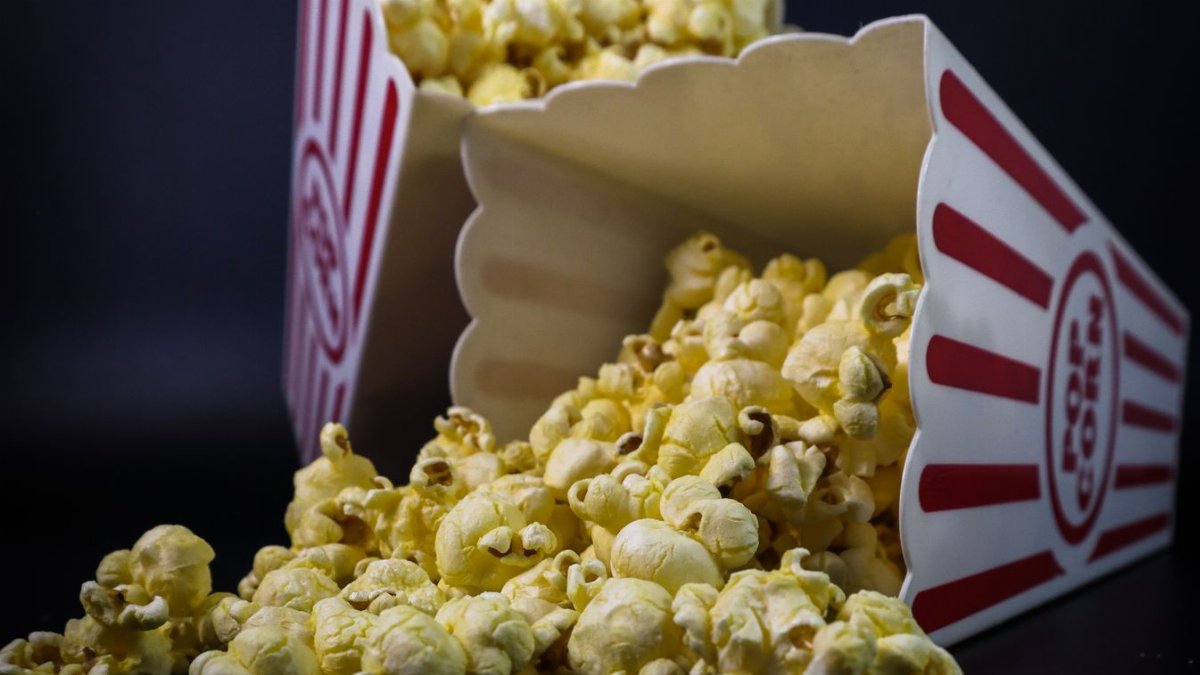 A still life photo of delicious freshly popped corn spilling from popcorn boxes.