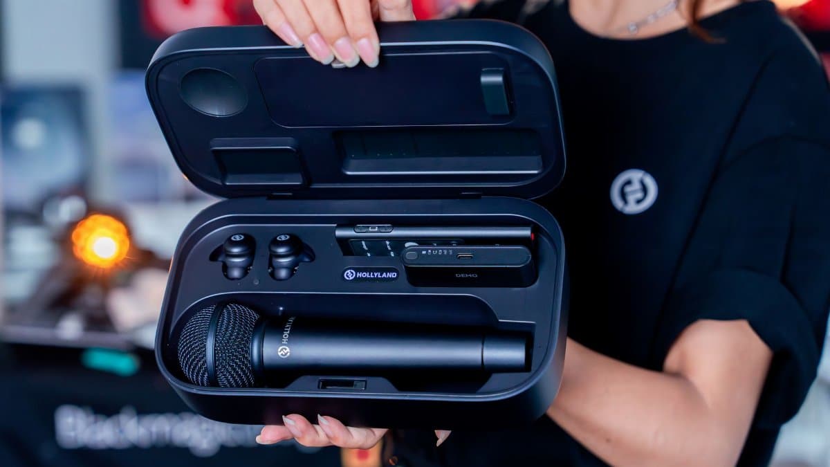 Hand holding a Hollyland wireless microphone set in a travel case.
