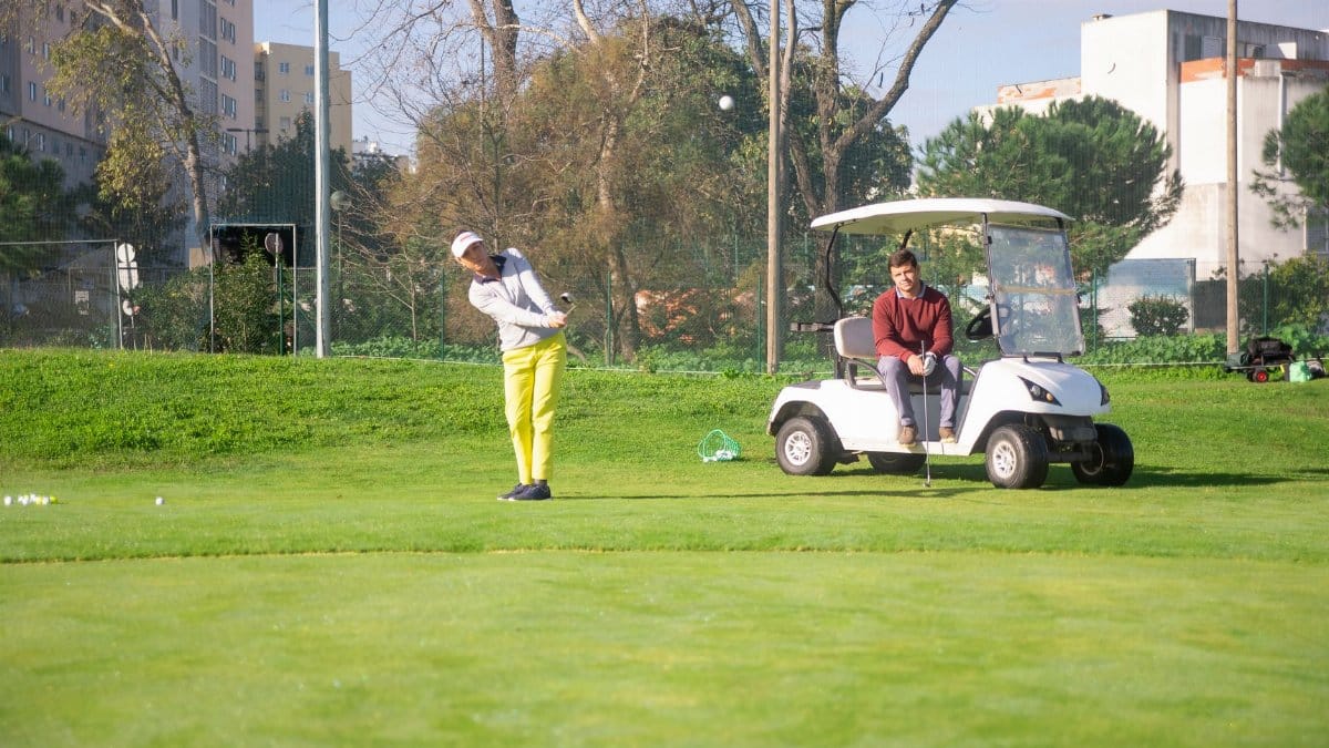 Two golfers enjoying a sunny day on a lush golf course in Portugal, surrounded by greenery.