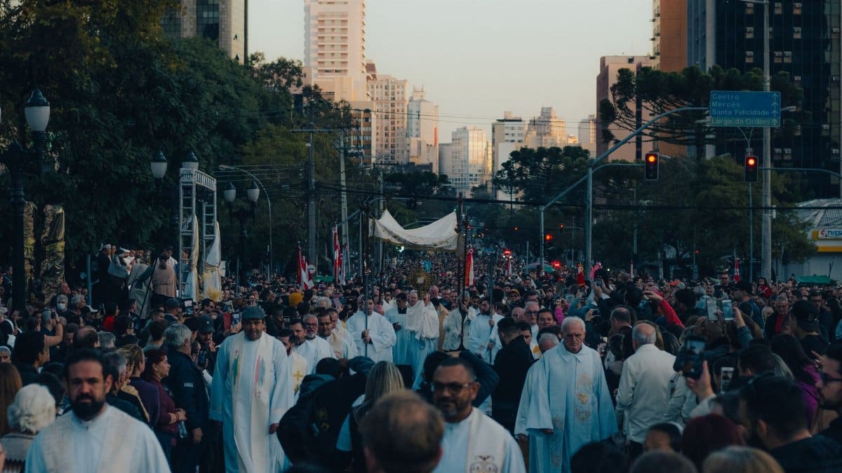 Crowd gathers for a religious procession in a bustling city center.