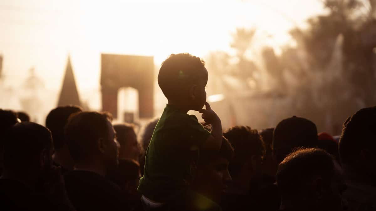 Crowd in Karbala Iraq silhouetted against the sunset, capturing a cultural festival moment.