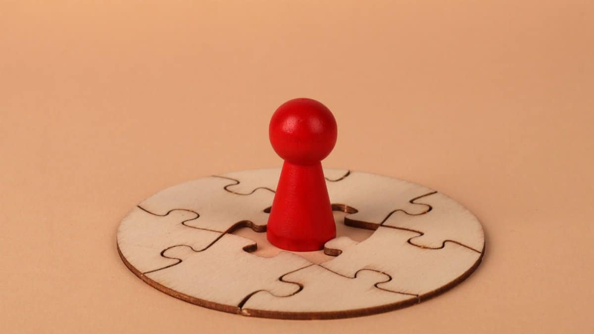 A red pawn stands on a wooden circular puzzle, symbolizing strategy and problem-solving.