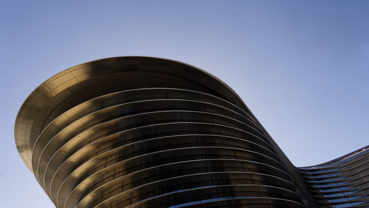 Low angle shot of modern curved architecture in Dubai, highlighting sleek design under a clear blue sky.