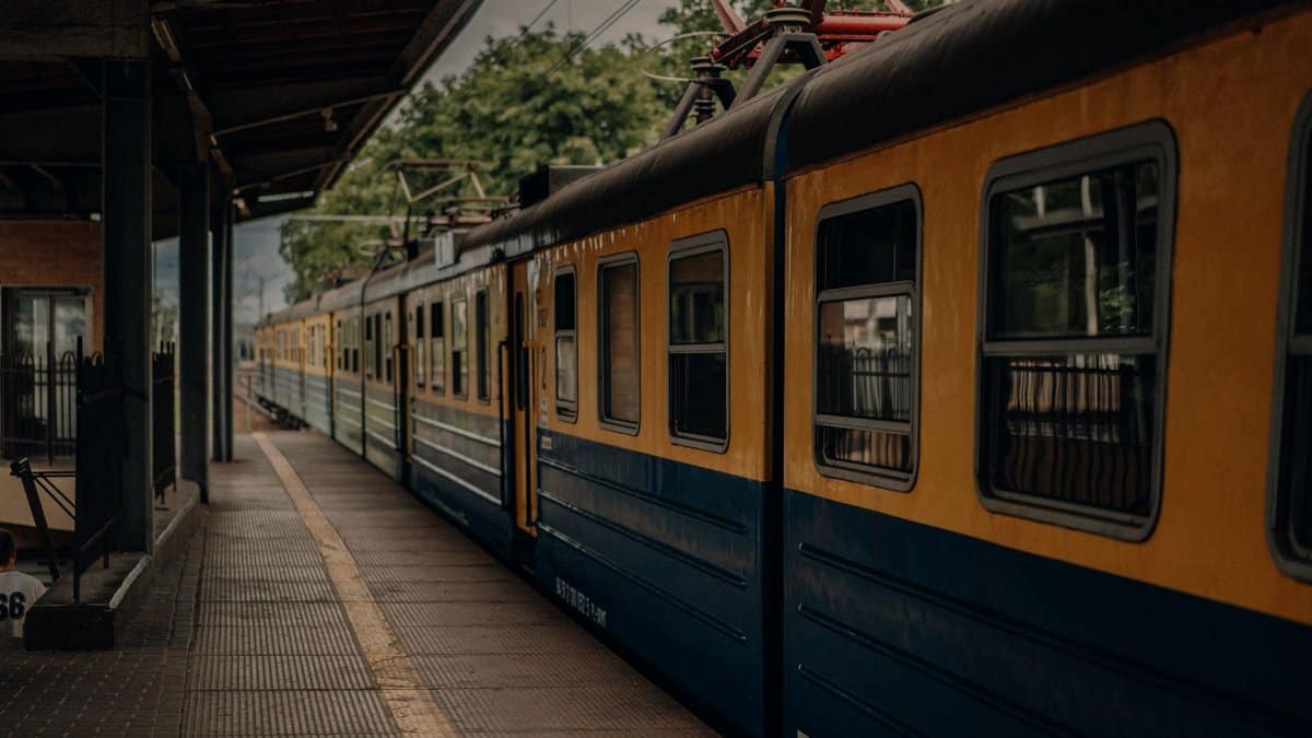 A yellow and blue train at an urban station, waiting for departure on a cloudy day.