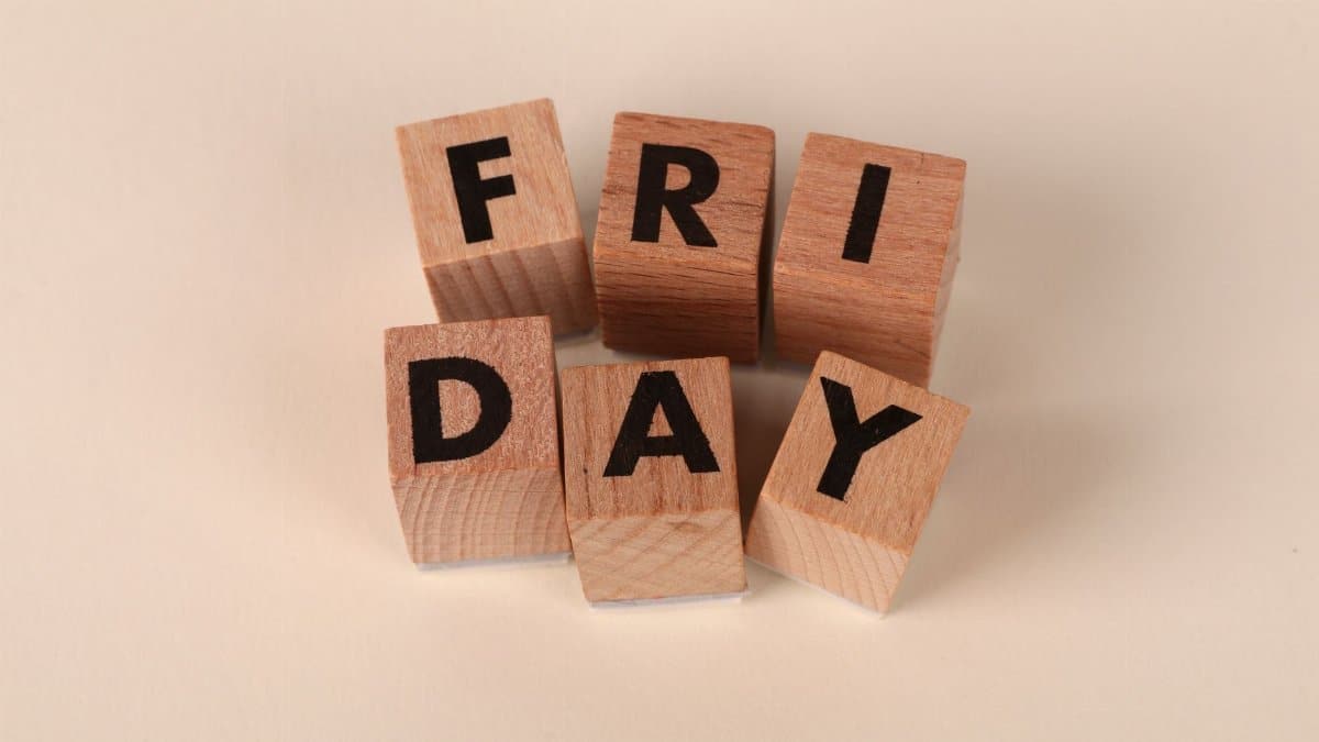 Wooden cubes spelling 'Friday' on a neutral surface with copy space.