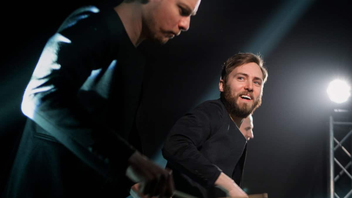 Dynamic drummers performing live on stage with focused lighting.