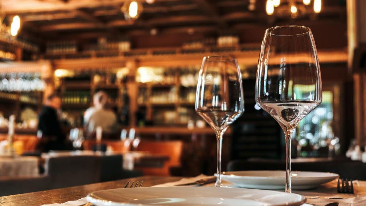 Elegantly set dining table with glassware in a cozy, warmly-lit restaurant ambiance.