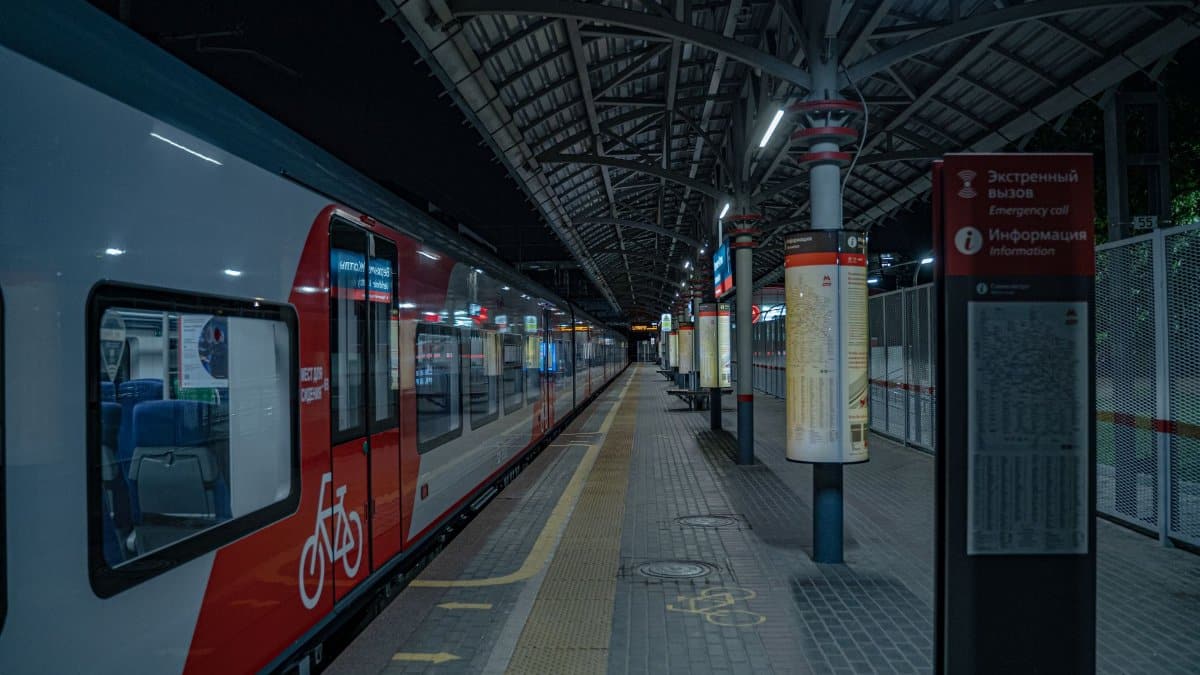 Wide-angle view of an urban train station at night with empty platform.