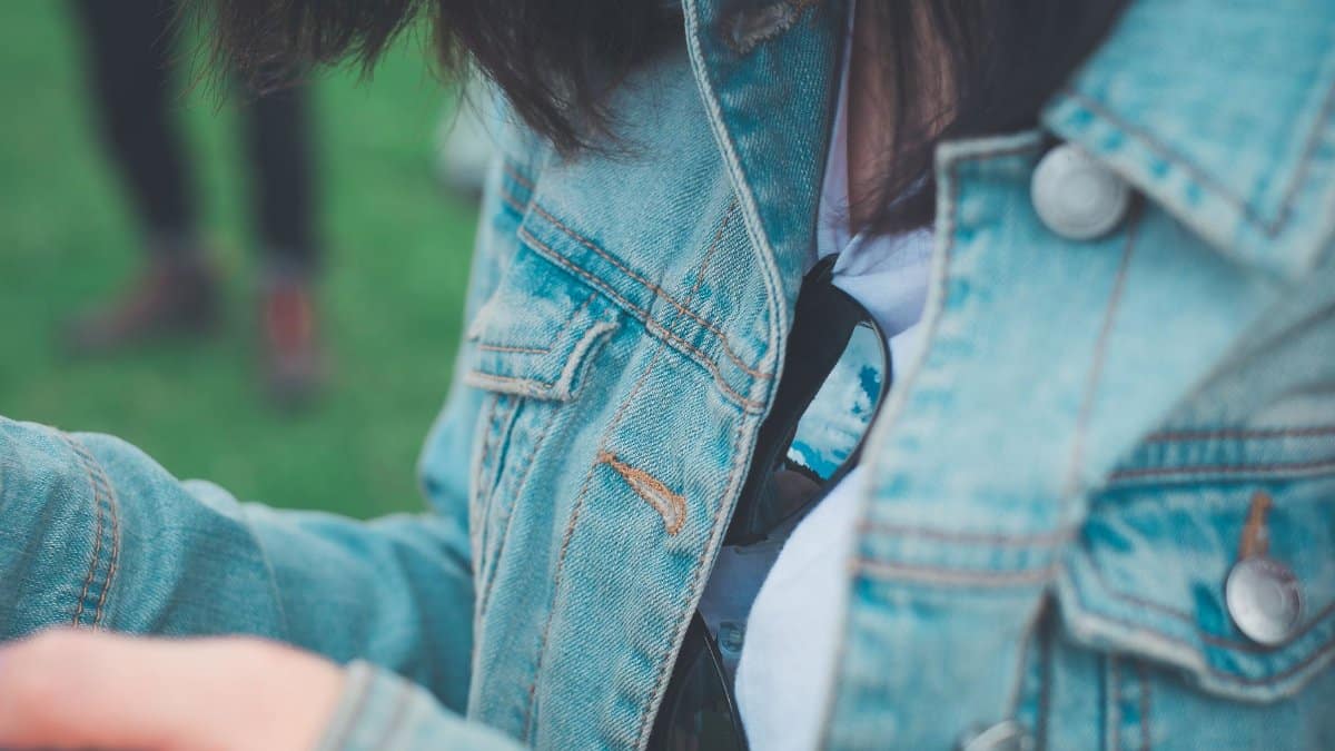 Casual fashion style with a denim jacket and sunglasses outdoors.