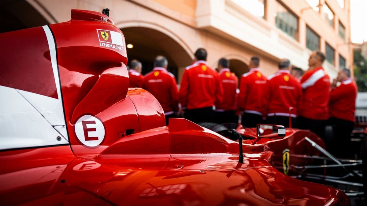 Close-up of a red Formula 1 car with team members in matching uniforms.