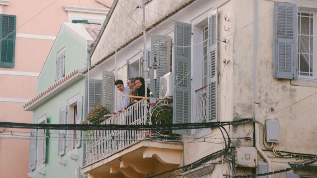 Candid scene of people on a classic Corfu balcony, depicting traditional Greek architecture.