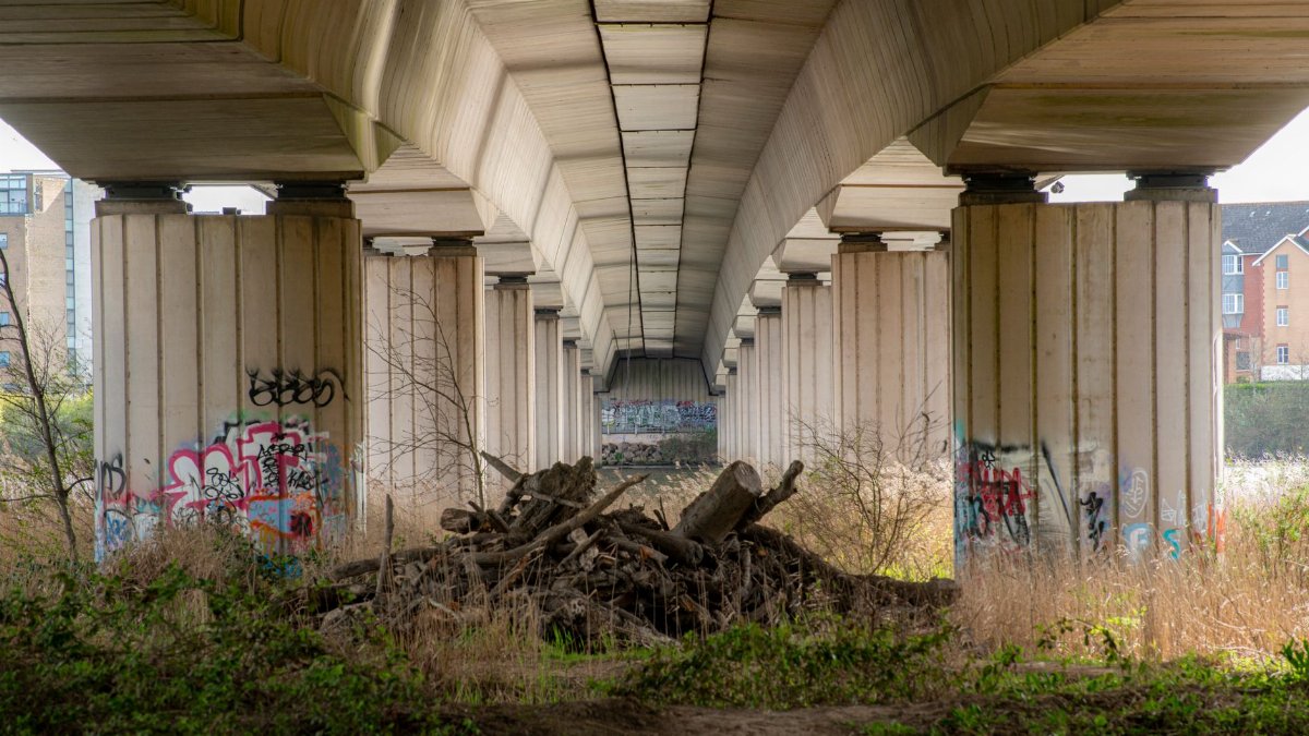 Dynamic view under Cardiff bridge showcasing urban graffiti and architectural design.