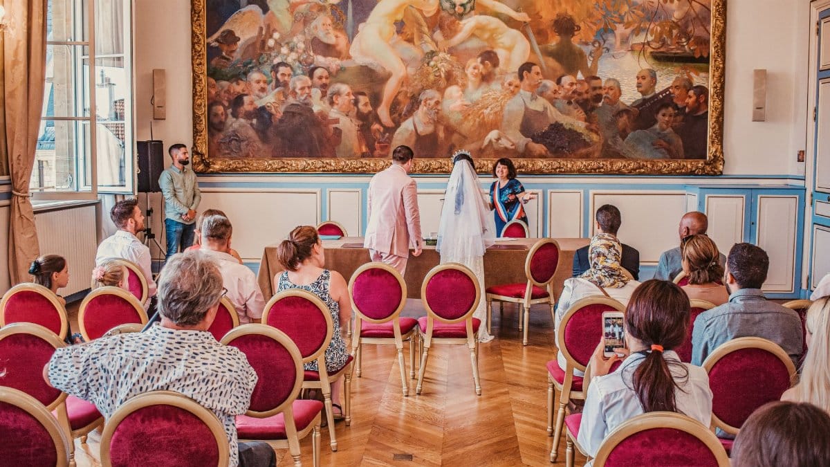 A beautiful wedding ceremony inside a Paris city hall, featuring a bride in a veil and groom with guests.