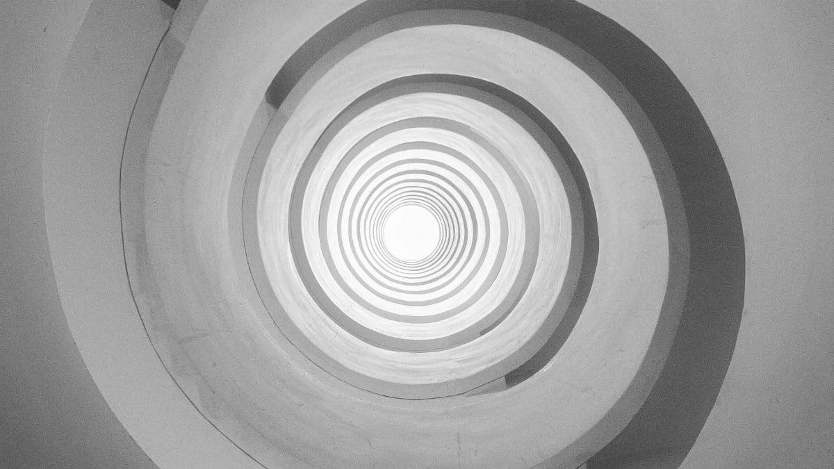Black and white abstract of a spiraling tunnel with concentric circles.