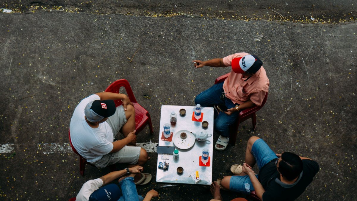 Overhead view of friends enjoying a casual outdoor coffee gathering.
