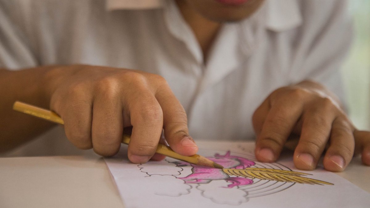 Close-up of a child deeply engaged in coloring with pencil crayons, showcasing creativity.