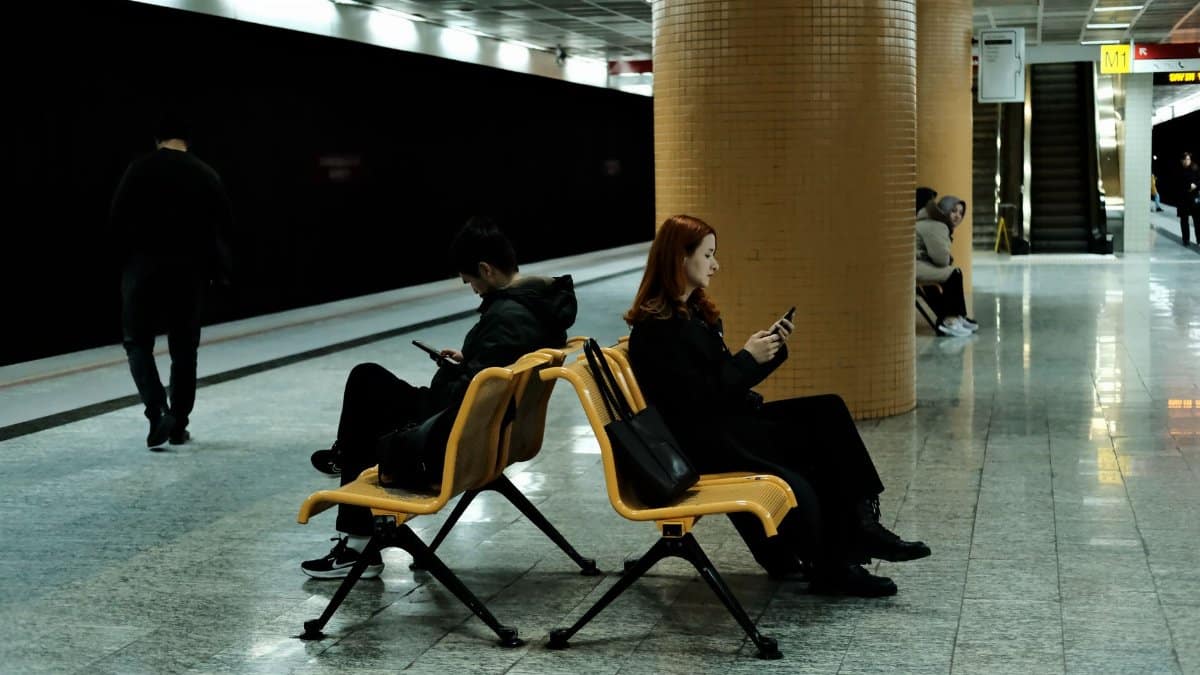 A quiet moment at a subway station with people absorbed in their phones.