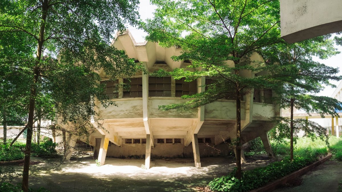 Explore a distinctive architectural design surrounded by lush greenery at a Hanoi university campus.