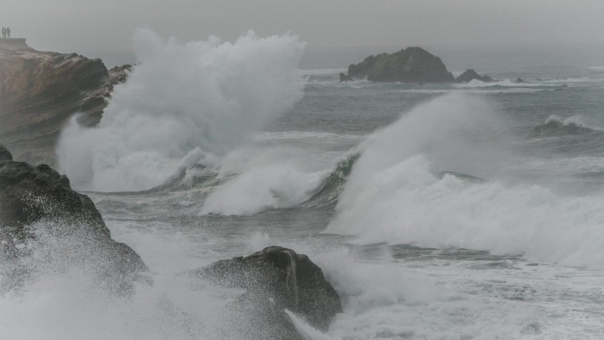 Powerful waves crashing against rocky cliffs on a misty day with a dramatic seascape.