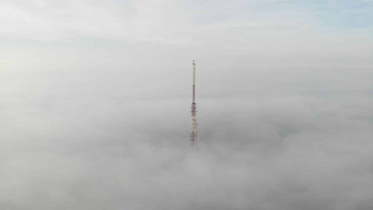 Aerial shot of a communication tower emerging through dense fog in Ukraine.