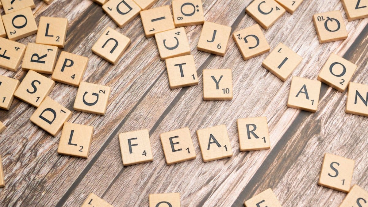 Scrabble tiles on wood surface spelling 'fear', representing emotions like dread and anxiety.