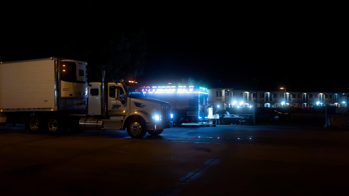 Two brightly lit trucks parked in an urban area at night, showcasing their vibrant lights.