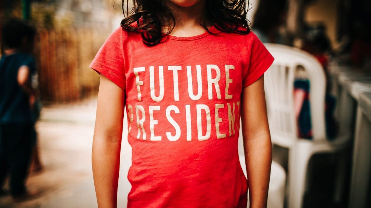 Crop anonymous child standing on street in t shirt with future president inscription