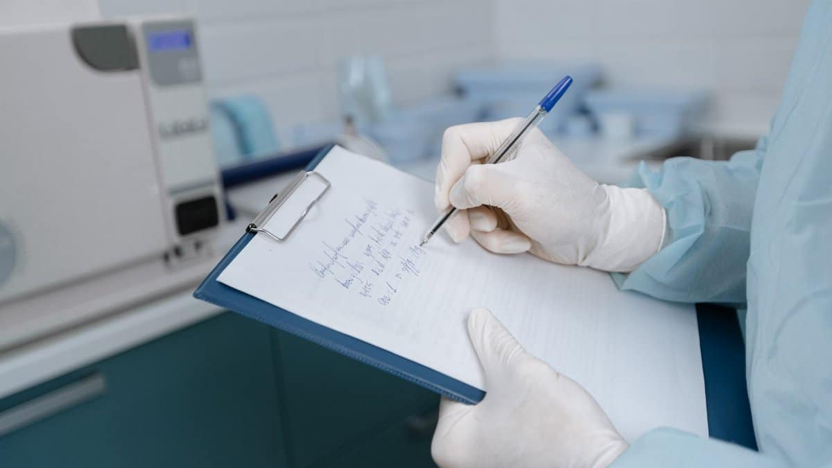 Medical worker in lab coat writing notes in a clinic setting.