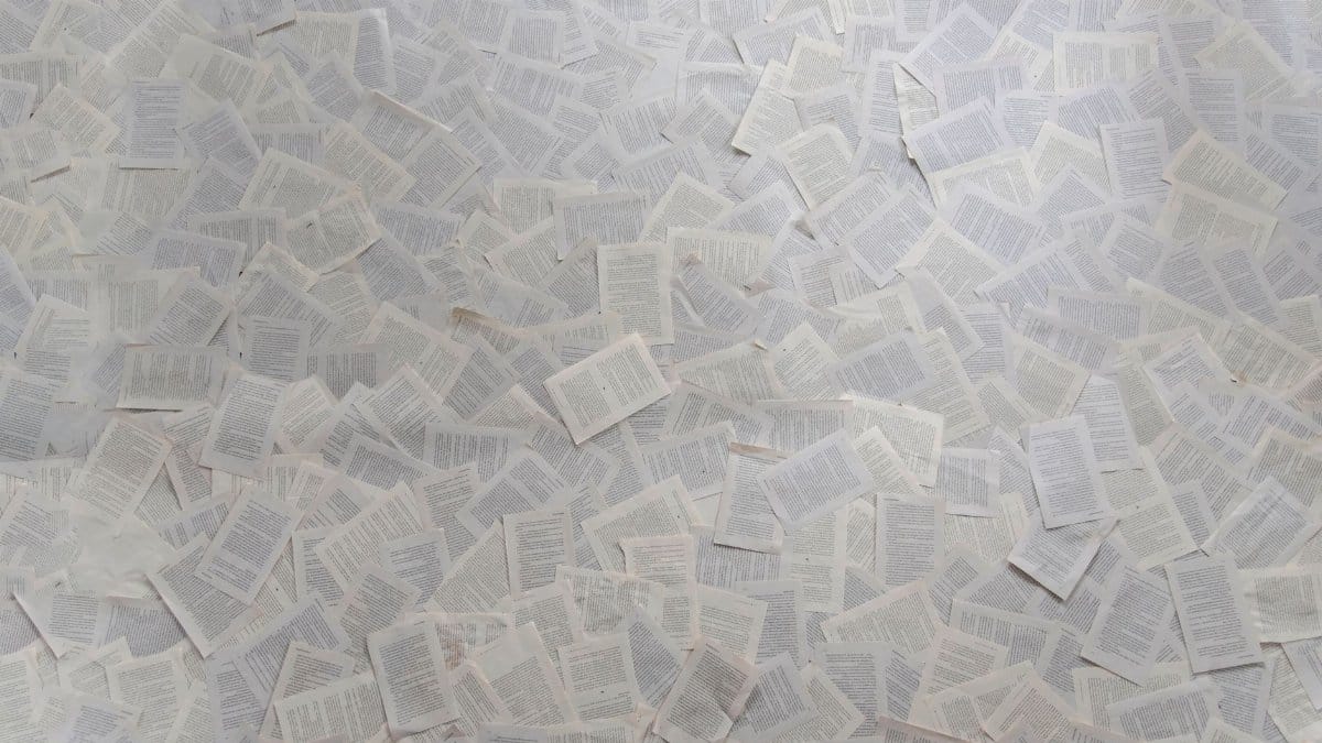 Abstract composition of numerous loose book pages overlapping indoors.