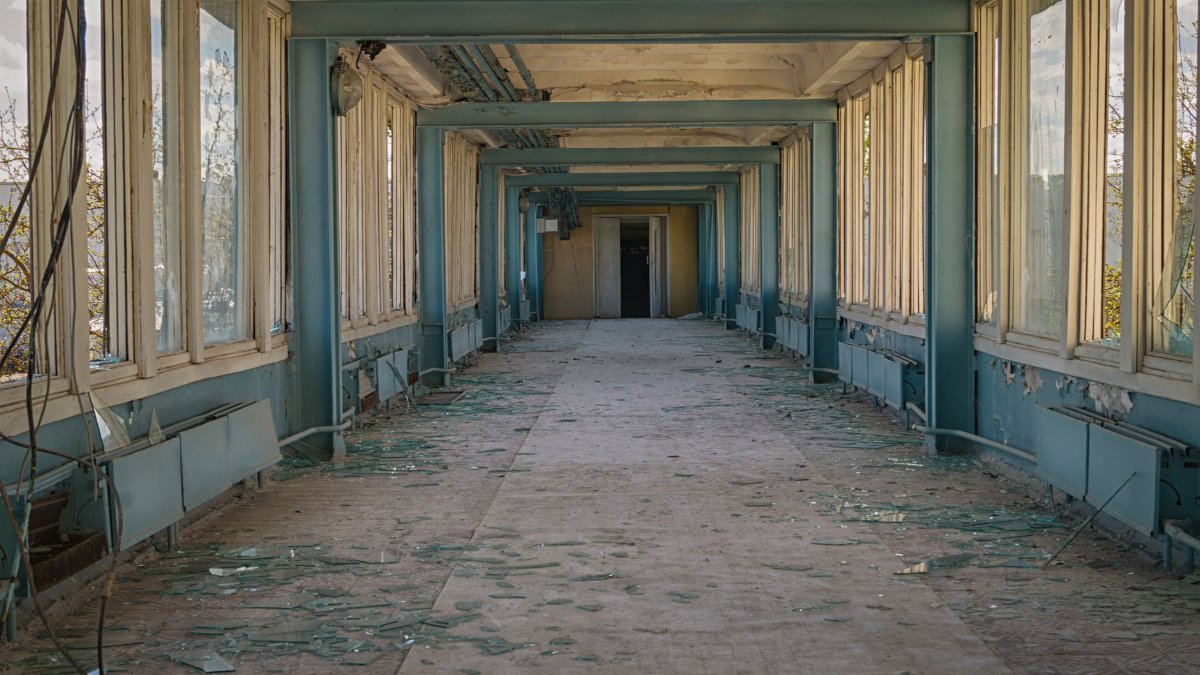 Explore the eerie charm of an abandoned corridor with shattered glass and peeling paint.