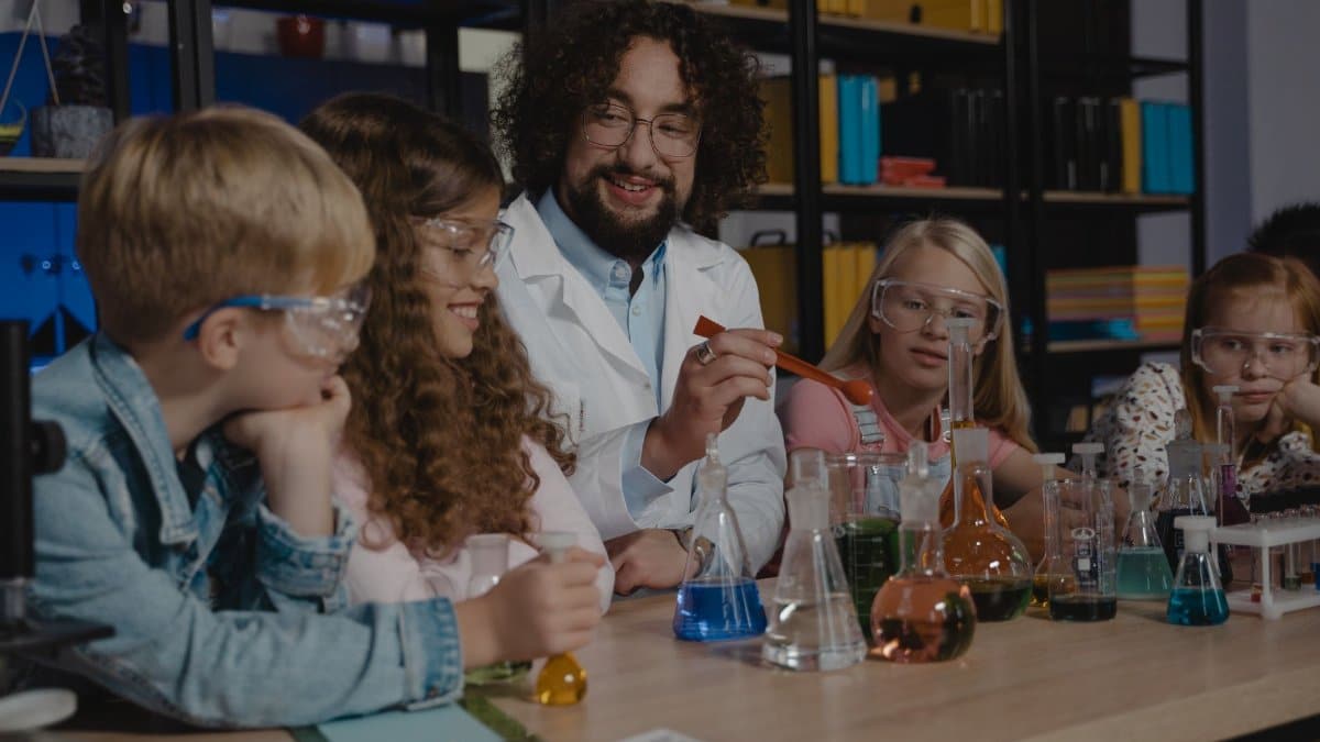 Students in a science class watch a chemistry experiment with colorful liquids.