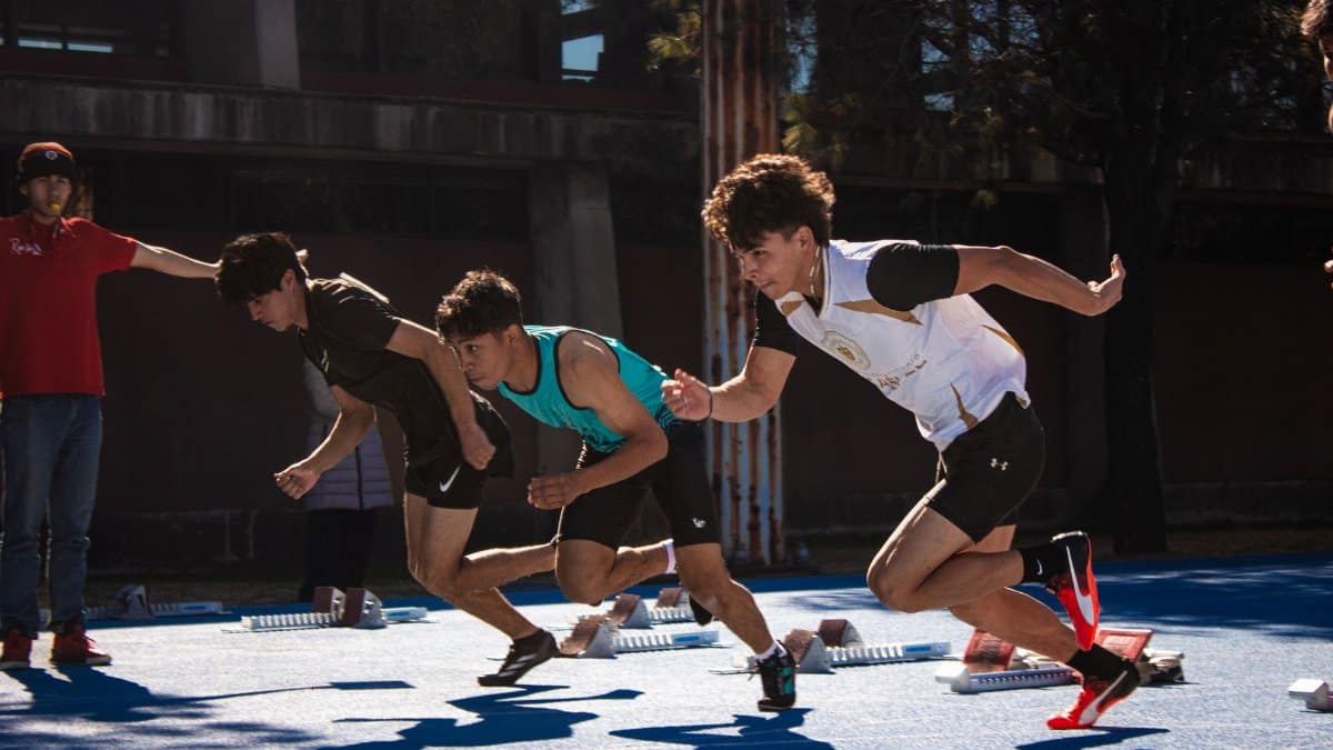 Dynamic action of male athletes sprinting from starting blocks on an outdoor track.
