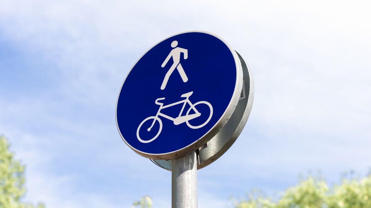 A blue road sign indicating a shared pedestrian and bicycle path under clear skies.