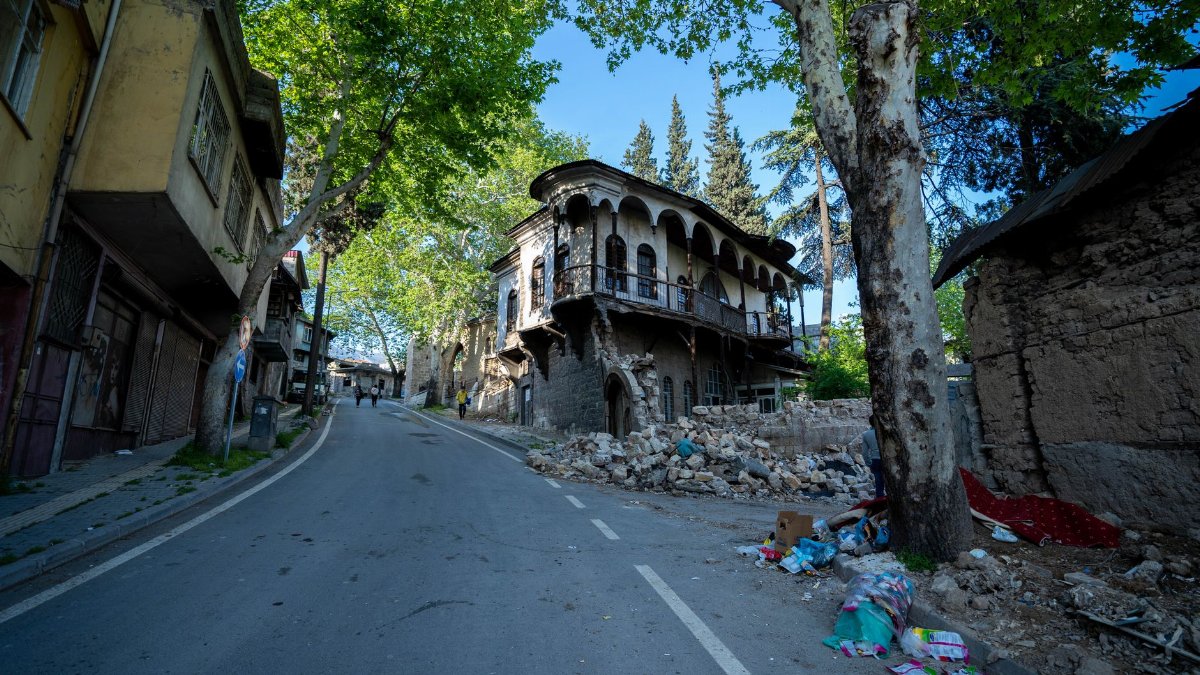 A deserted street with a historic building in ruins, surrounded by trees and debris.