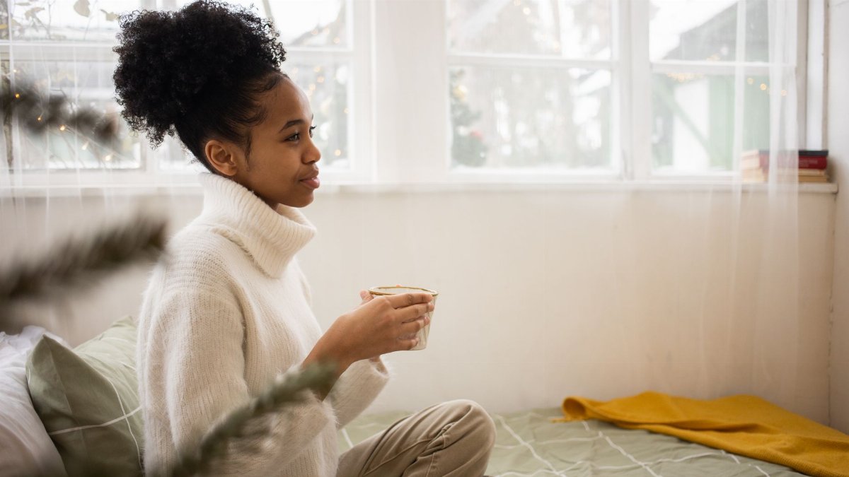 Young woman enjoying a warm drink on a cozy morning indoors.