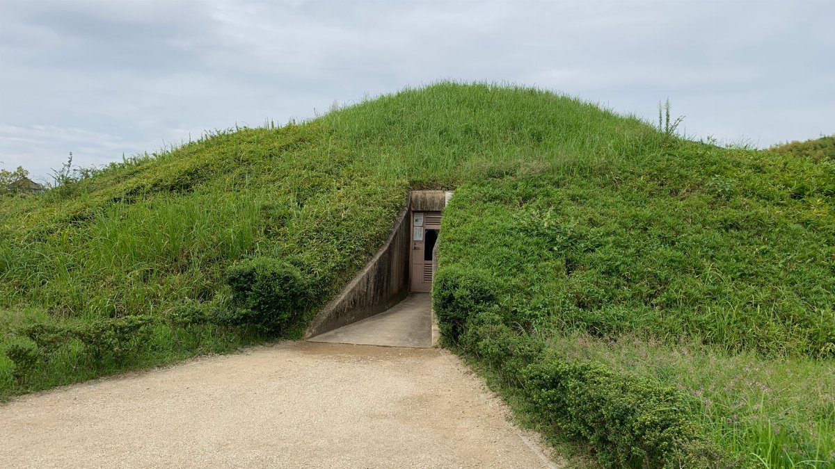 Grass-covered burial mound with entrance in Nara, Japan. Overcast day scene.