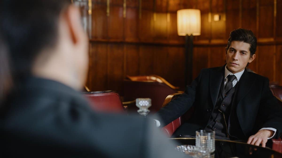 Businessman in a classic suit seated elegantly in a vintage style setting, exuding authority.