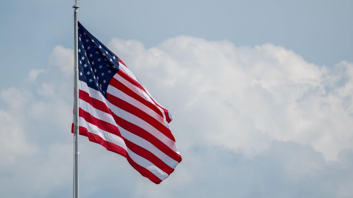 A vibrant American flag waving on a flagpole with a cloudy sky backdrop, symbolizing national pride.