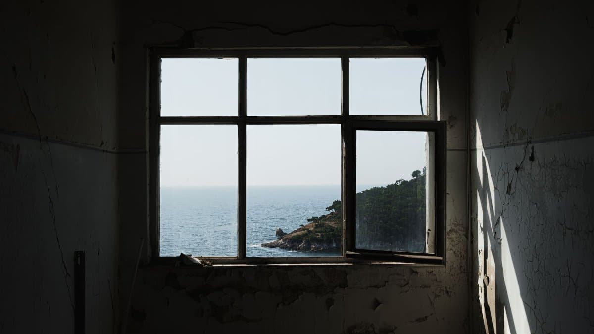 A weathered room with a scenic ocean view framed by a large window.