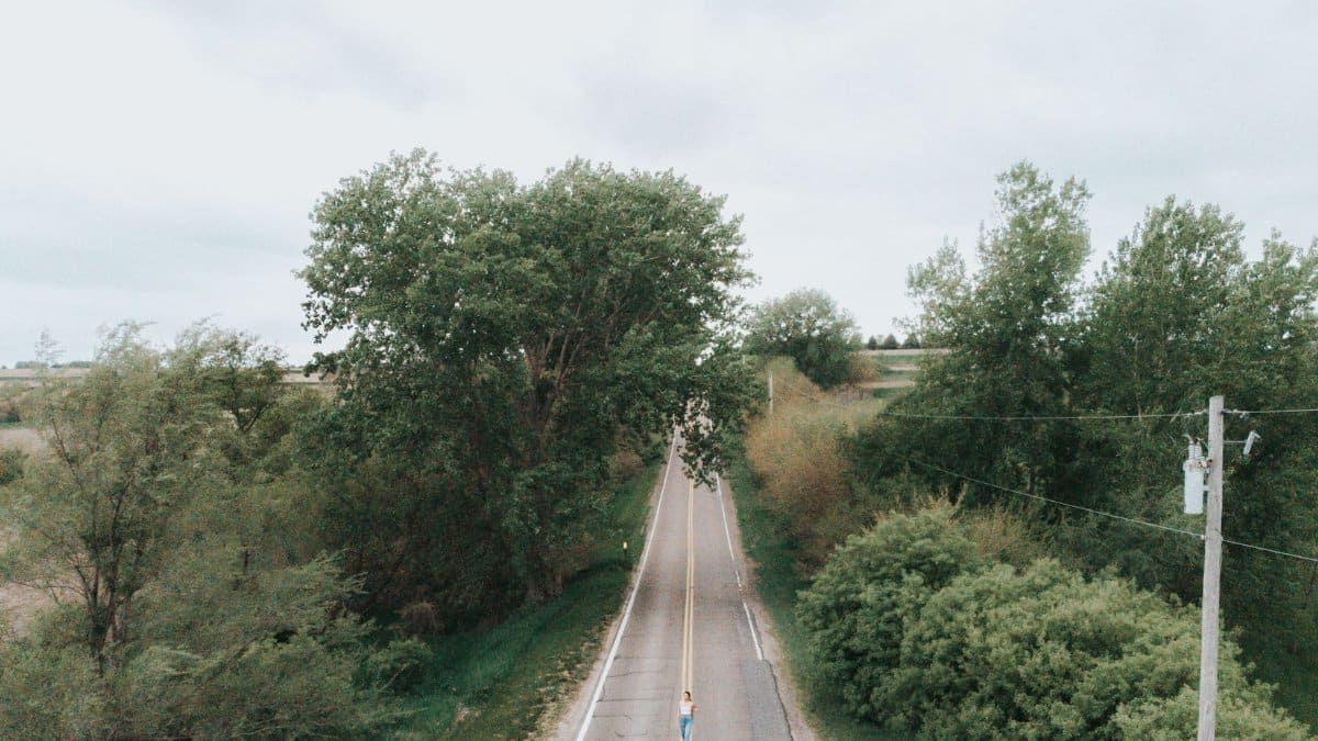 Drone image capturing a woman on a rural road surrounded by lush greenery in Omaha, Nebraska.