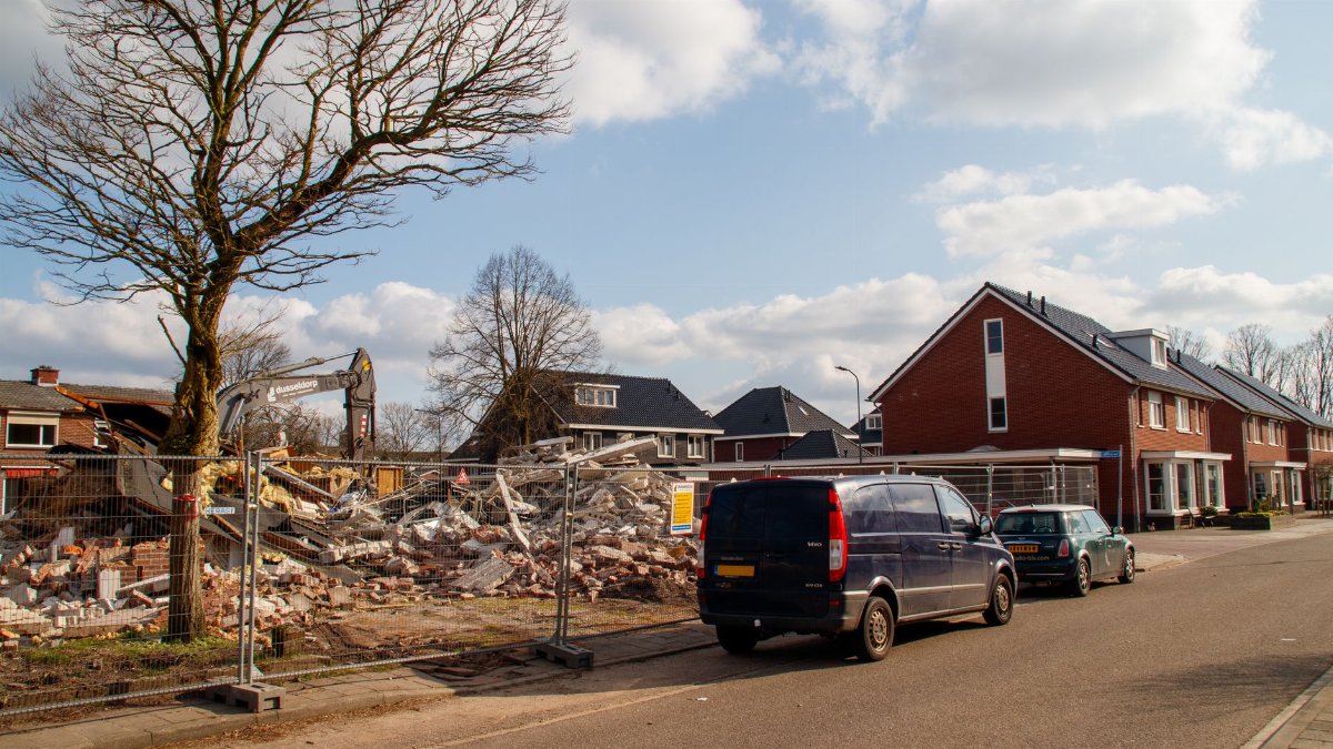Residential neighborhood with a building under demolition and construction equipment in view.