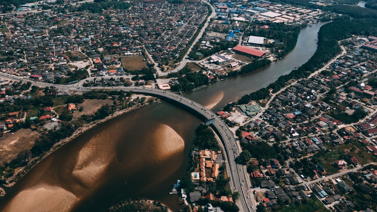 High-altitude urban cityscape featuring a winding river and highway bridge.