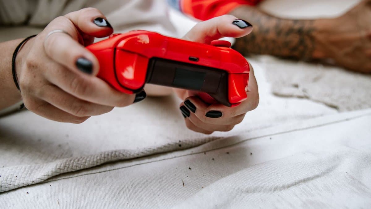 Close-up of hands holding a red game controller, perfect for gaming and technology themes.